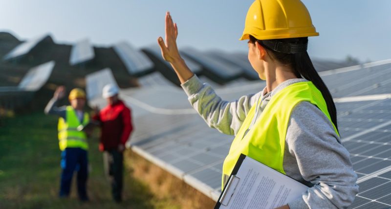 mujer-ingeniera-tecnologa-parada-paneles-solares-saludando-sus-colegas-mujer-casco-protector-uniforme1